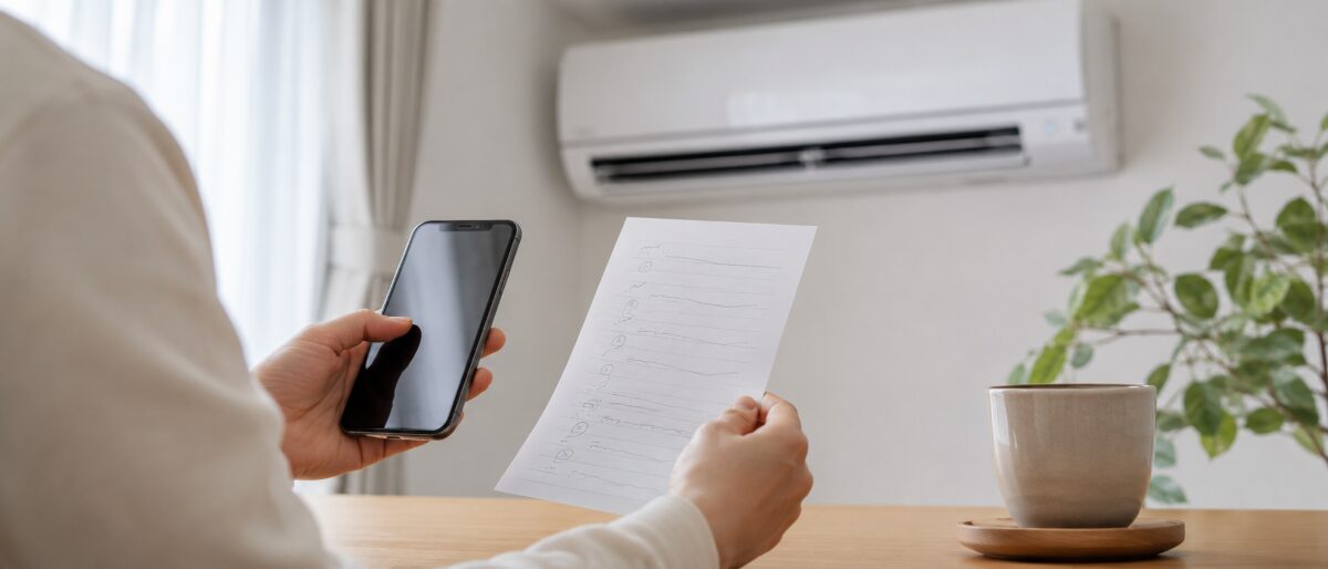 エアコン掃除の見積もり項目をスマホとメモで確認している様子