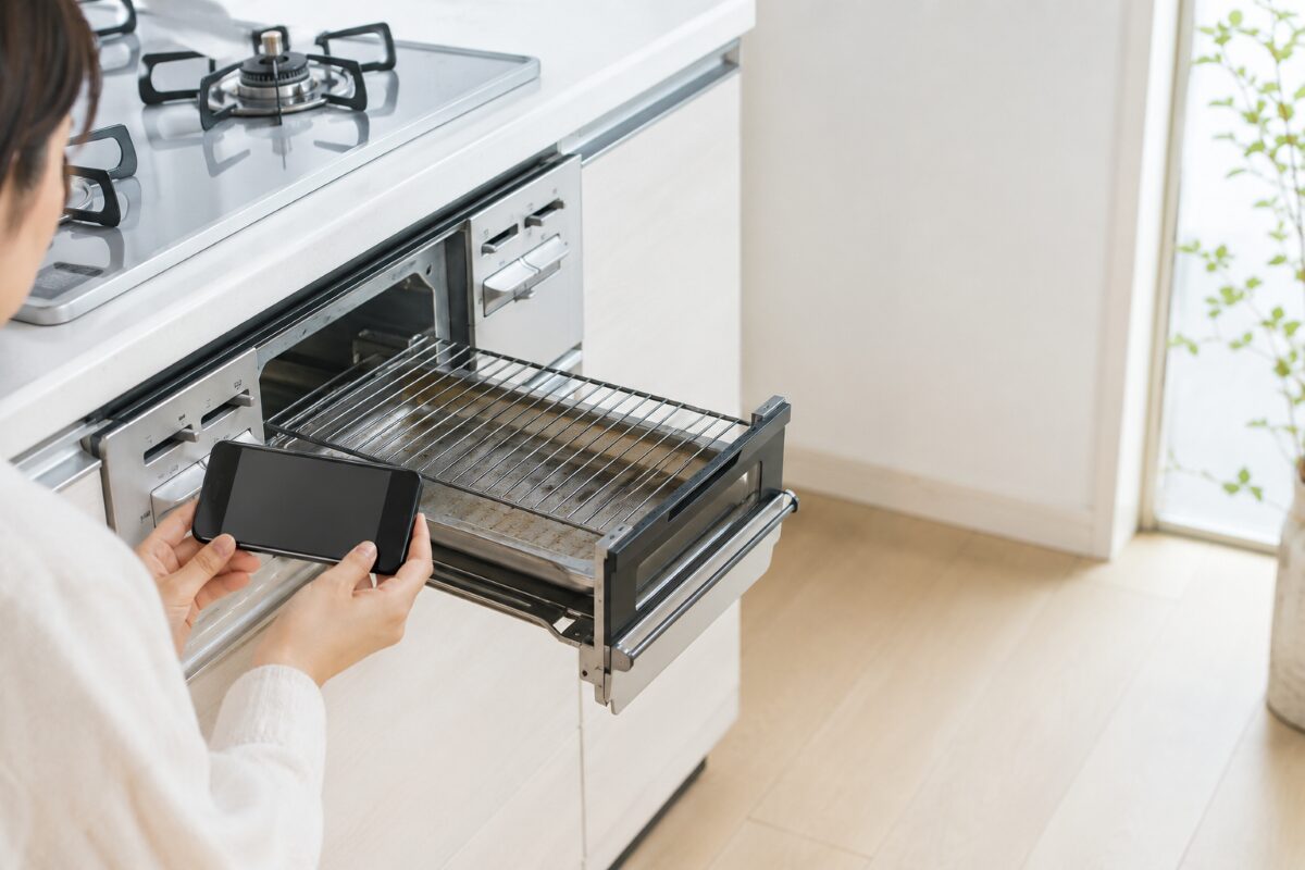魚焼きグリルの全体と庫内をスマートフォンで撮影する様子